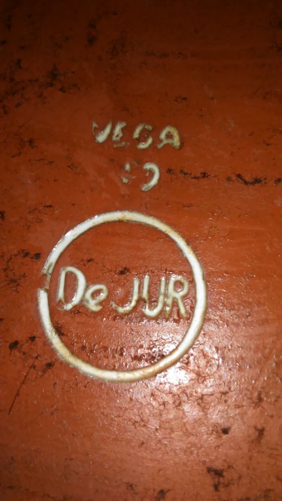 While it looks like Eduardo Vega, I have never seen his signature without the slash through the G. I found that DeJur is the name of a camera or company, which then makes the design make lots of sense; but the back was covered by felt, ehich I removed.