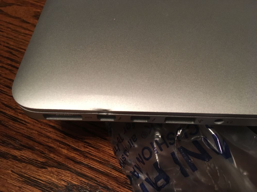 Damage to the side of the laptop -- the whole side is pushed in, with the apex of the dent at the rearmost Thunderbolt. (image uploaded to dispute)