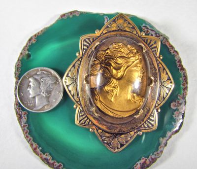 Reverse intaglio cameo backed with gold, and set in a rolled gold , sawtooth brooch with decidely aesthetic motif.